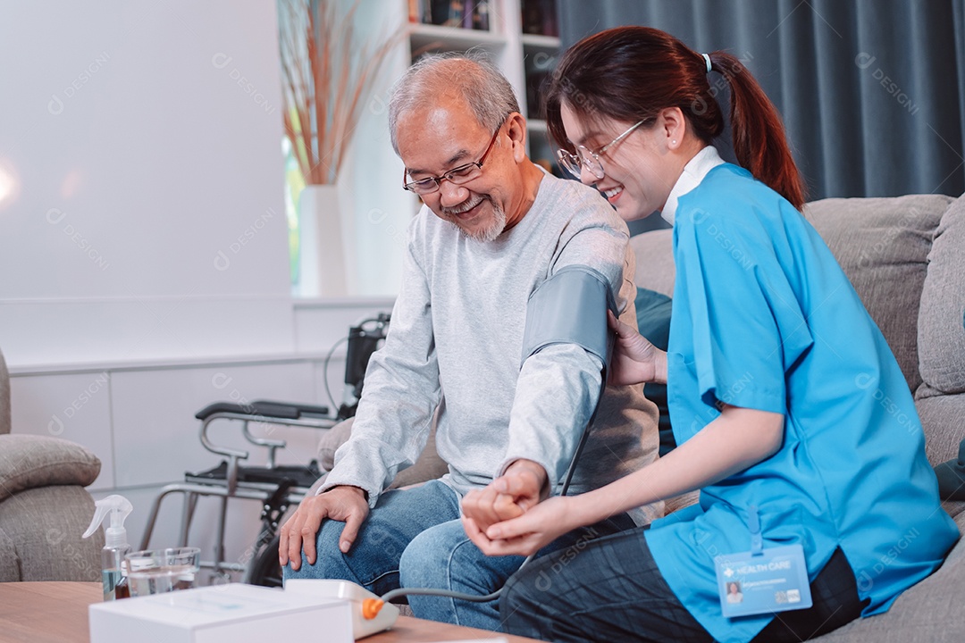O médico cuidador asiático examina o medidor de pressão arterial de uso de paciente mais velho.
