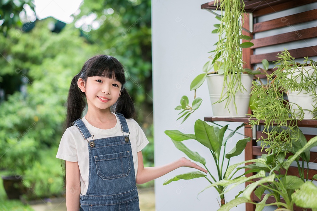 Menina asiática sorridente apresenta plantas no jardim em casa.