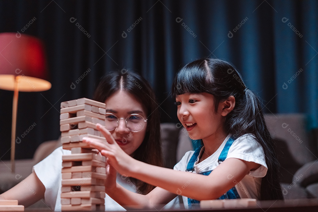 A família feliz asiática da filha joga bloco de madeira de brinquedo em casa.