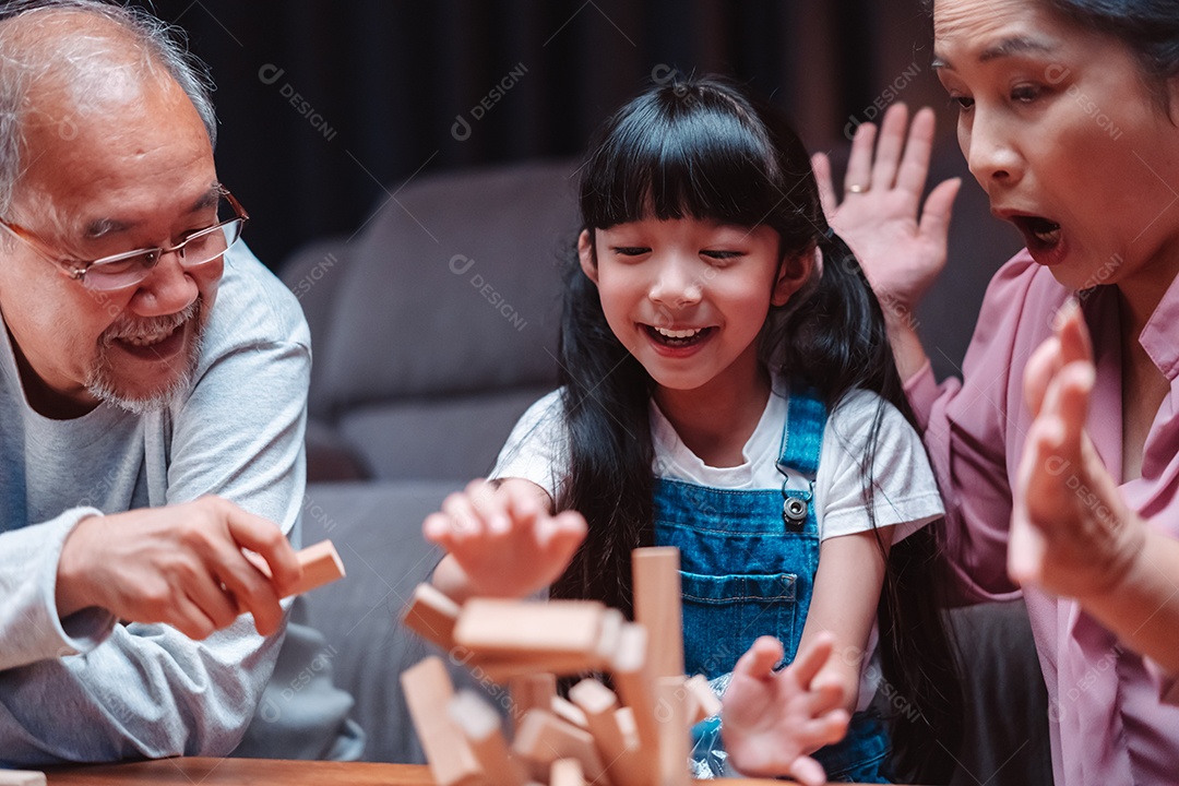 A família feliz asiática da filha joga bloco de madeira de brinquedo em casa.