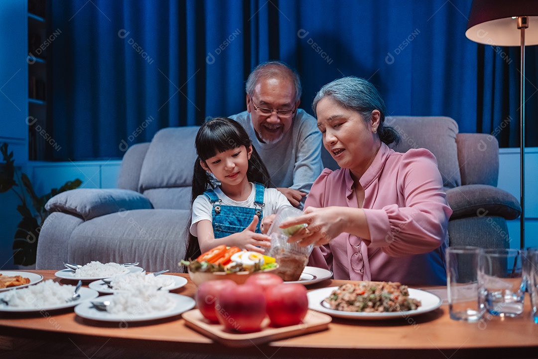 Família feliz asiática de garotinha soprando velas no bolo.