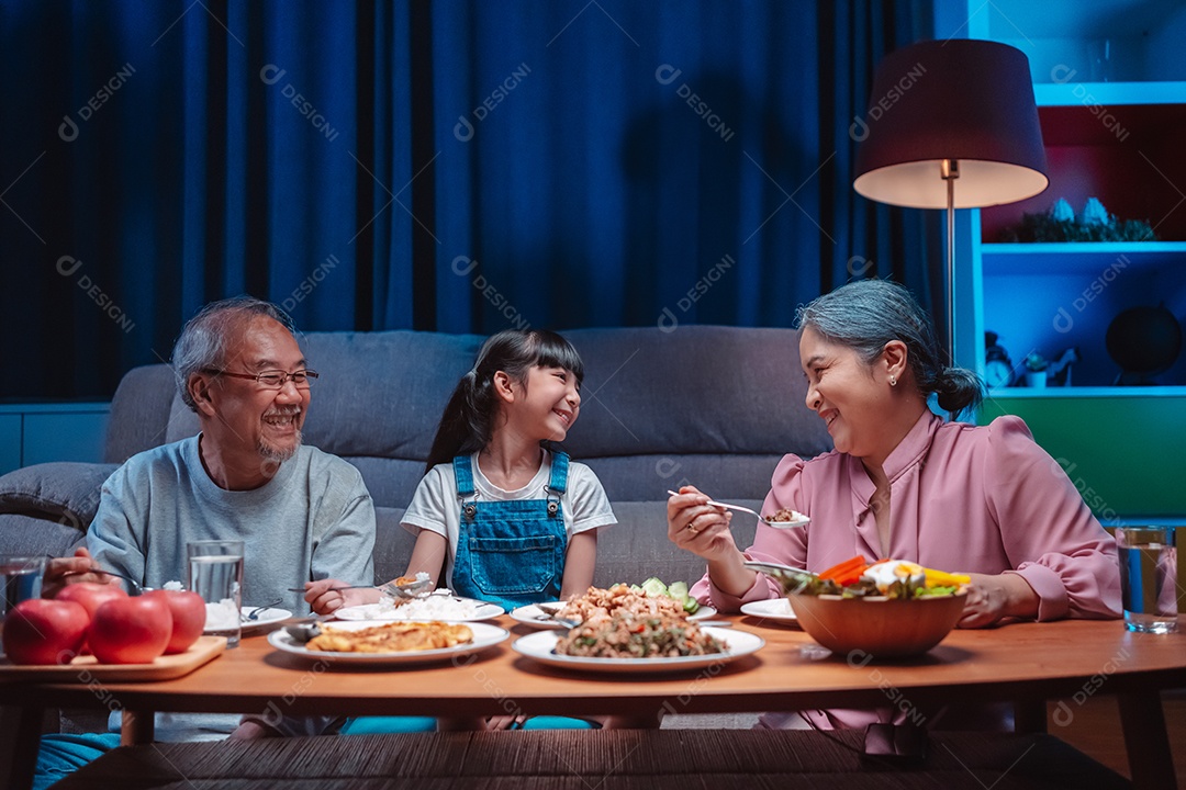 Família feliz asiática almoçando na mesa japonesa de jantar sorrindo juntos.
