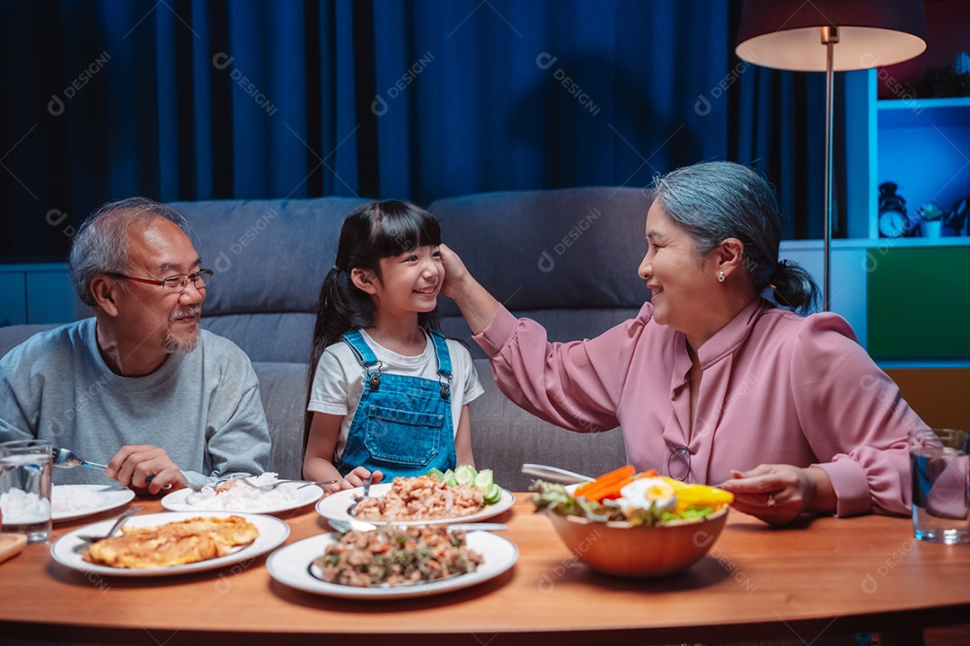 Família feliz asiática almoçando na mesa japonesa de jantar sorrindo juntos.