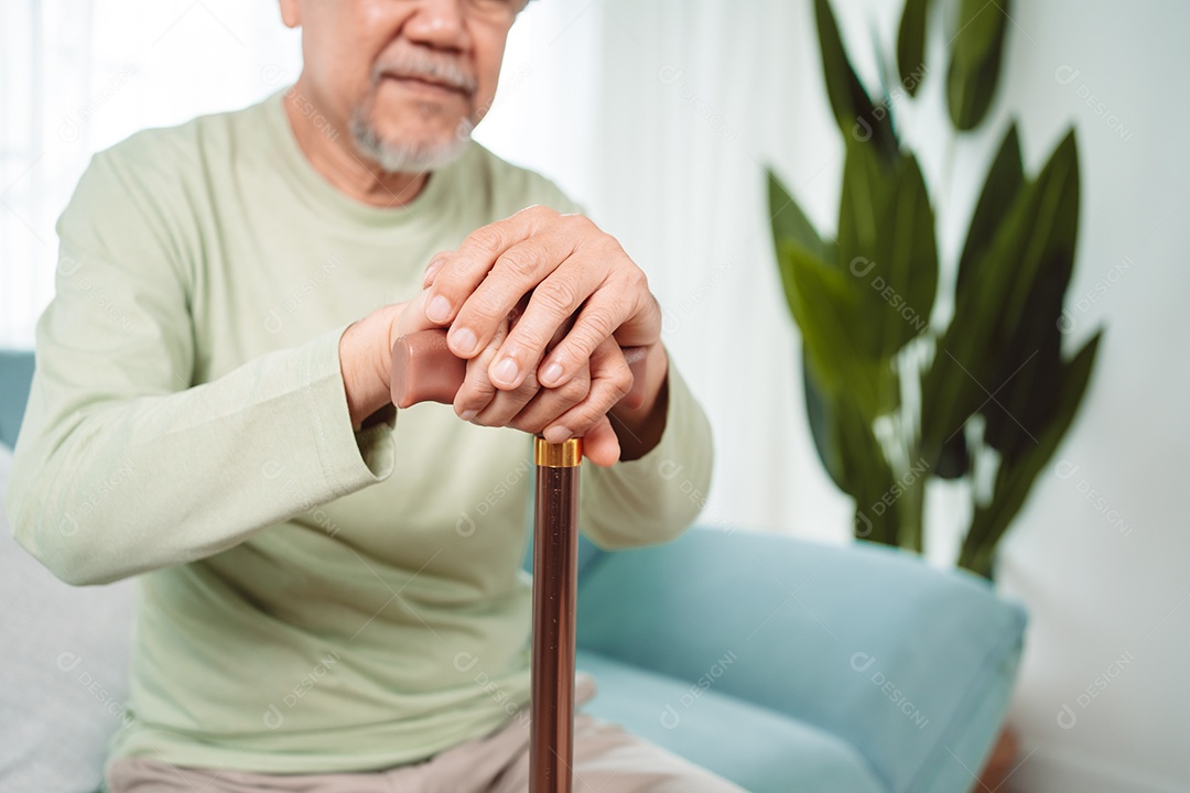 Sorrindo feliz do velho idoso asiático sentado no sofá com andador ou bengala em casa