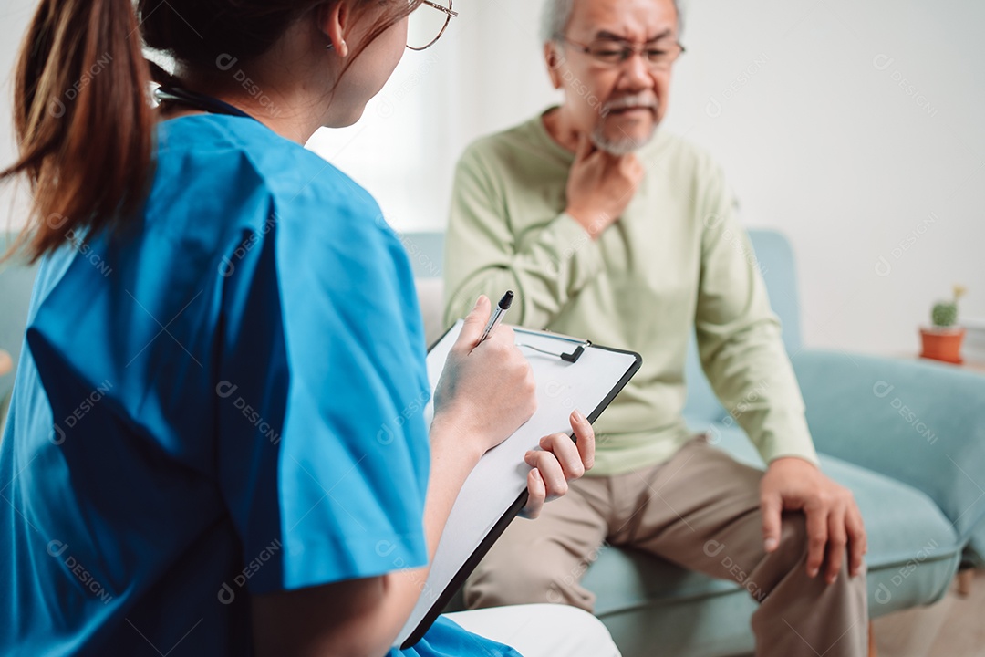 Cuidador asiático falando sobre check-up de paciente masculino sênior na sala de estar em casa.