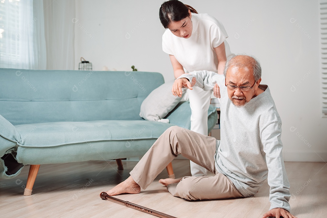 Mulher asiática ajudando o homem sênior que caiu no chão na sala de estar em casa.