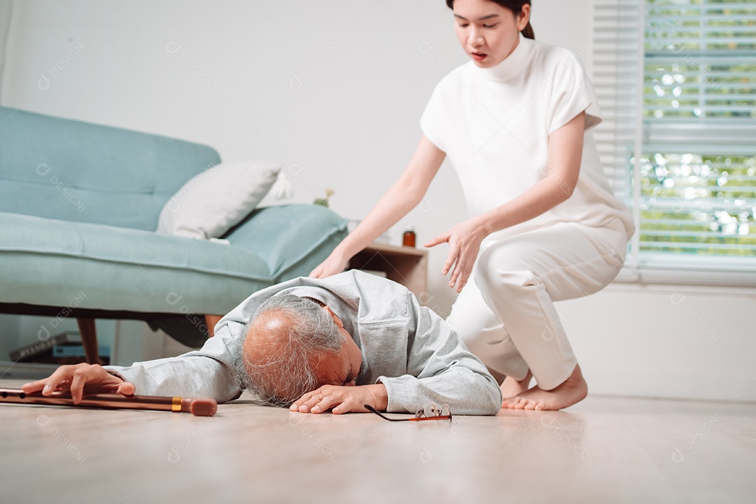 Mulher asiática ajudando o homem sênior que caiu no chão na sala de estar em casa.