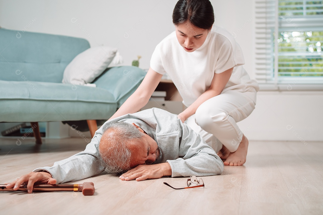 Mulher asiática ajudando o homem sênior que caiu no chão na sala de estar em casa.