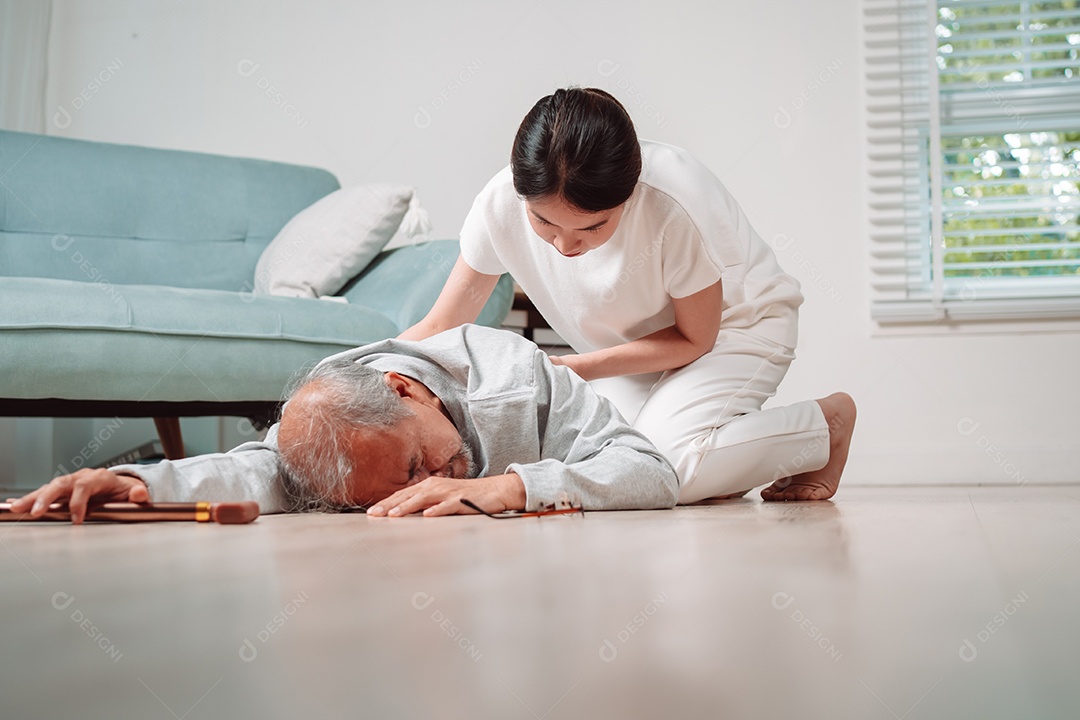 Mulher asiática ajudando o homem sênior que caiu no chão na sala de estar em casa.