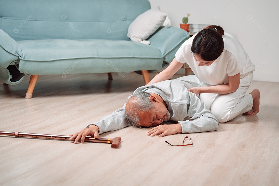 Mulher asiática ajudando o homem sênior que caiu no chão na sala de estar em casa.