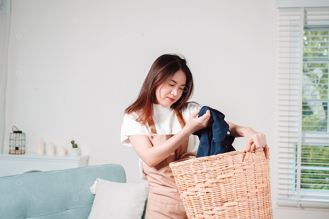 Mulher asiática fazendo tarefas domésticas leva roupas sujas no cesto
