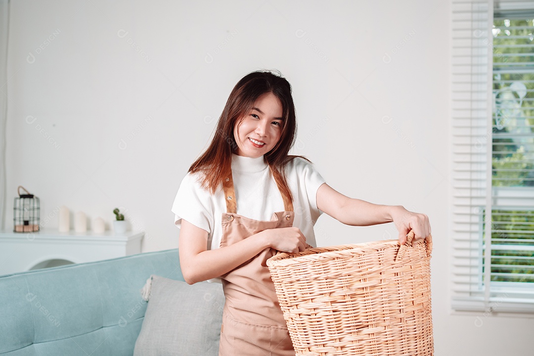 Mulher asiática fazendo tarefas domésticas leva roupas sujas no cesto