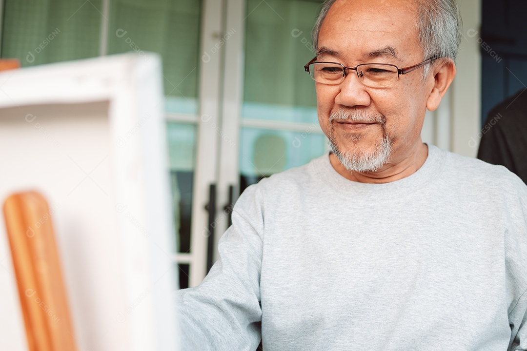 Homem sênior alegre pintando tela no quintal de casa