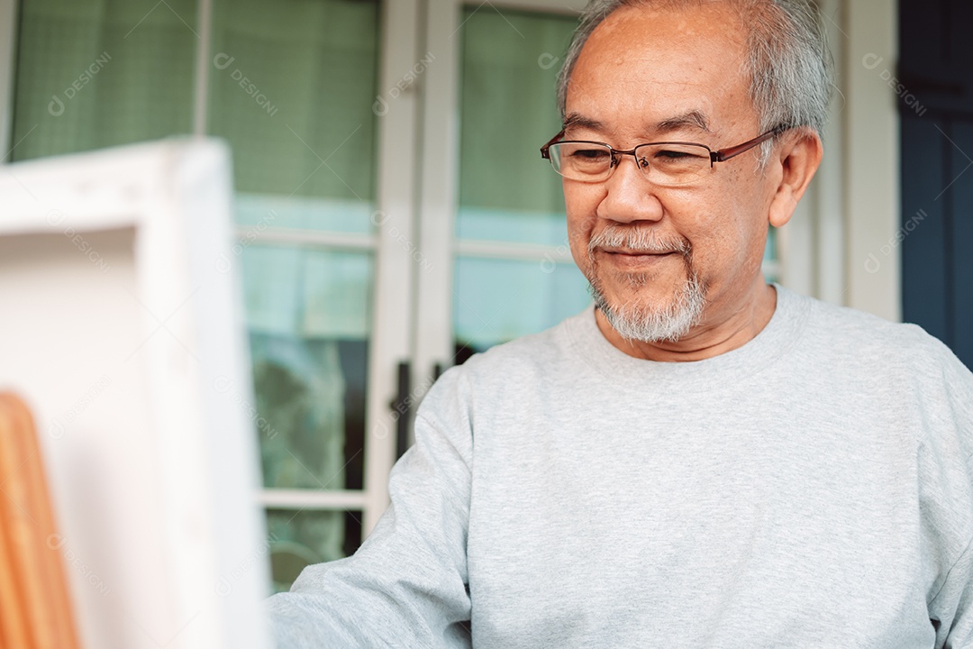 Homem sênior alegre pintando tela no quintal de casa