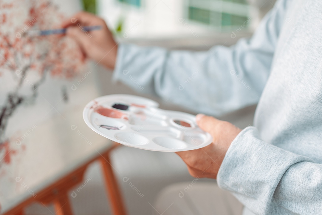 Homem sênior alegre pintando tela no quintal de casa