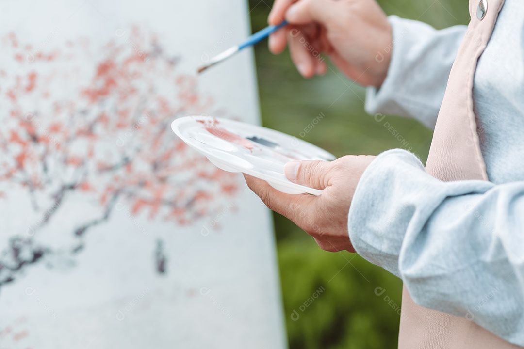 Homem sênior alegre pintando tela no quintal de casa