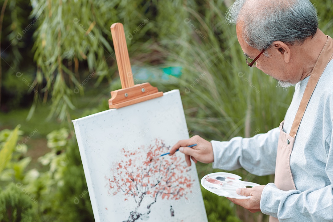 Homem sênior alegre pintando tela no quintal de casa