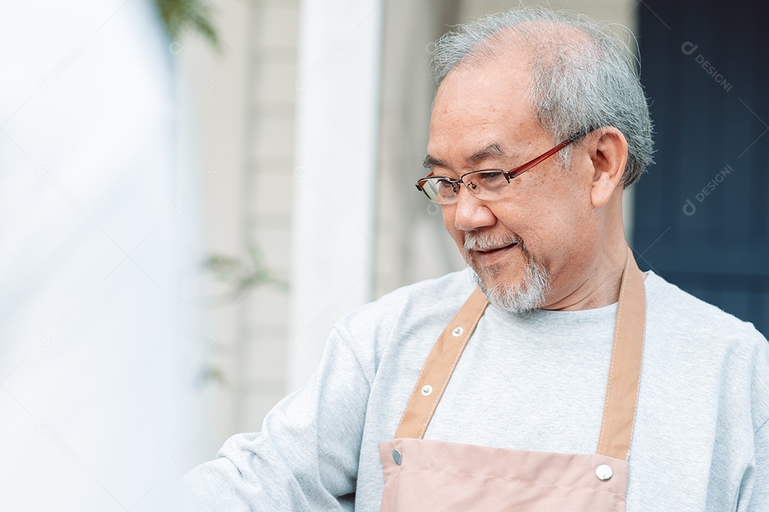 Homem sênior alegre pintando tela no quintal de casa