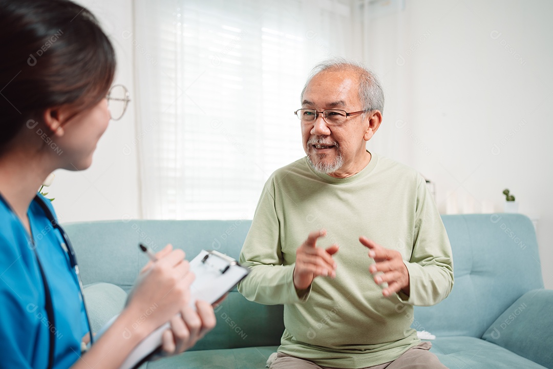 Cuidador asiático falando sobre check-up de paciente masculino sênior na sala de estar em casa.