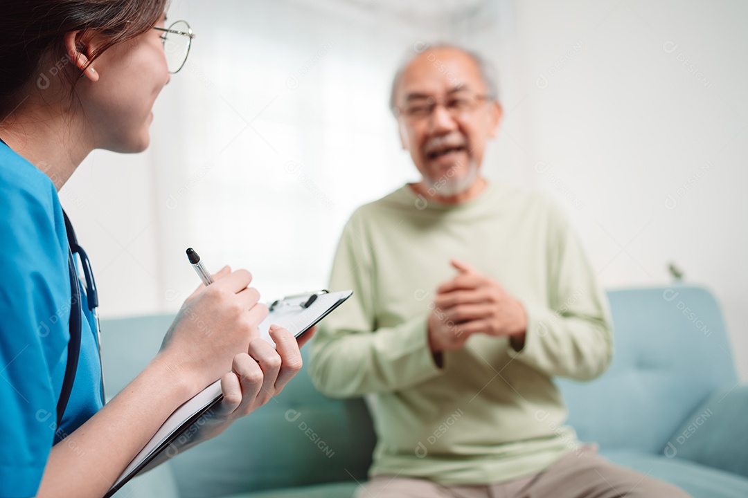 Cuidador asiático falando sobre check-up de paciente masculino sênior na sala de estar em casa.