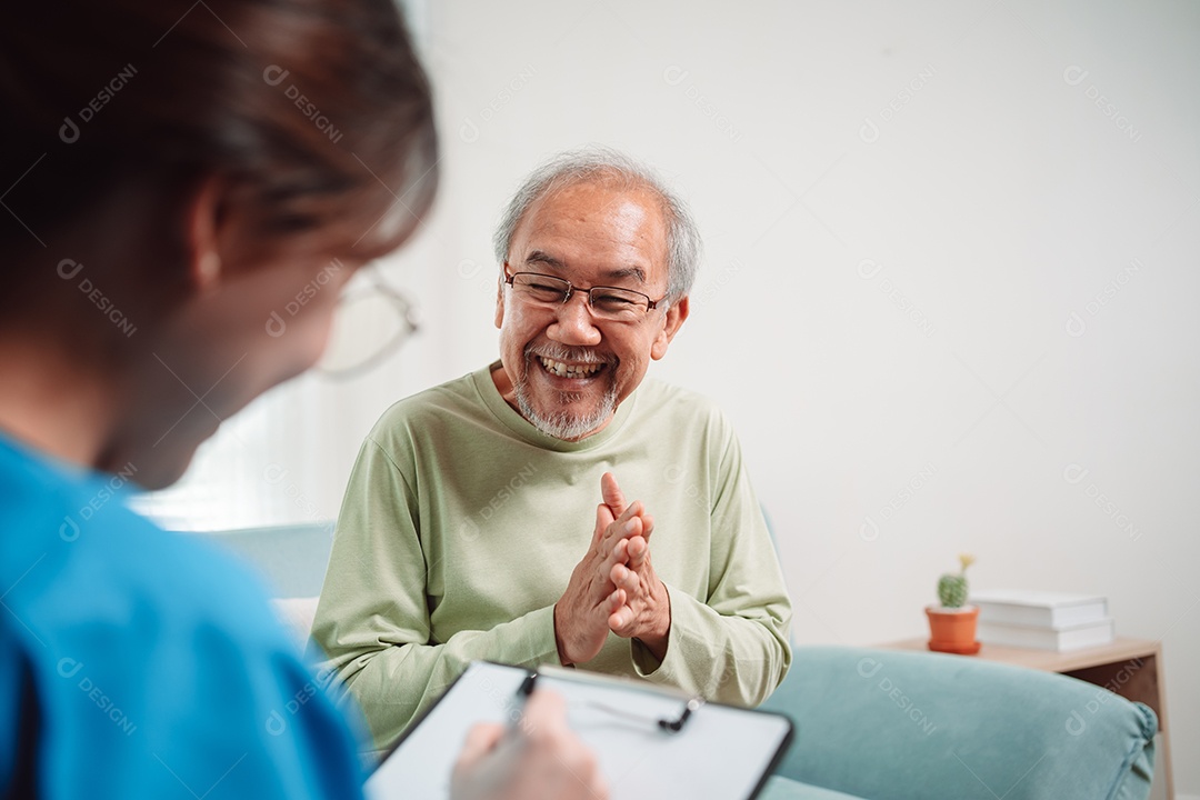 Cuidador asiático falando sobre check-up de paciente masculino sênior na sala de estar em casa.