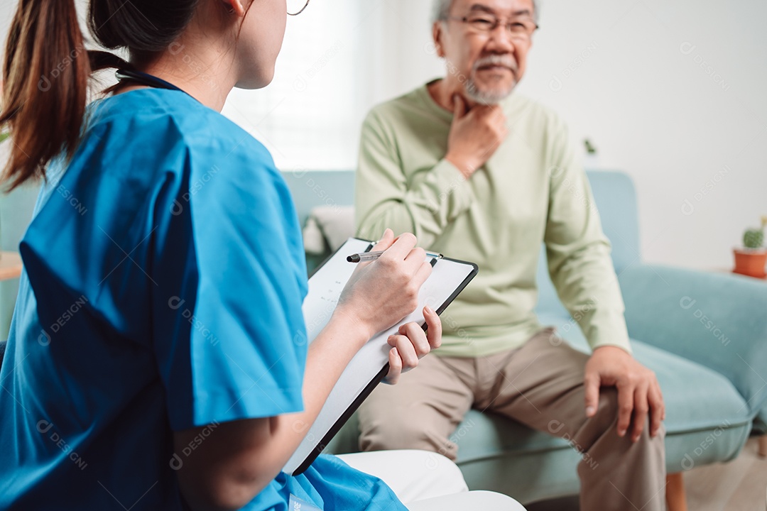 Cuidador asiático falando sobre check-up de paciente masculino sênior na sala de estar em casa.