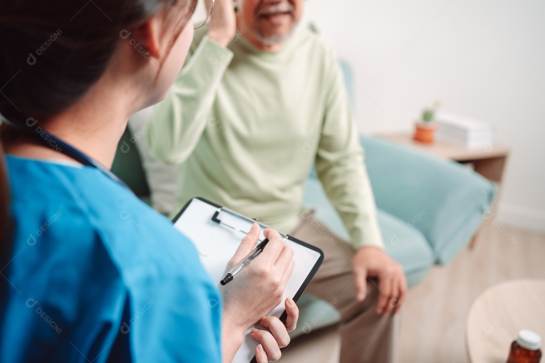 Cuidador asiático falando sobre check-up de paciente masculino sênior na sala de estar em casa.