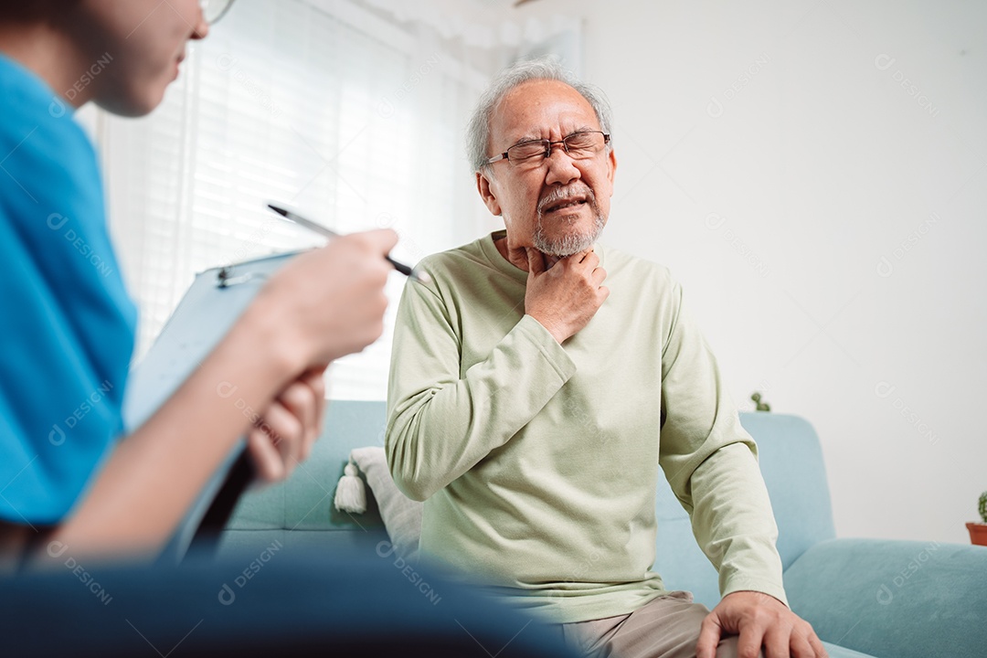 Cuidador asiático falando sobre check-up de paciente masculino sênior na sala de estar em casa.