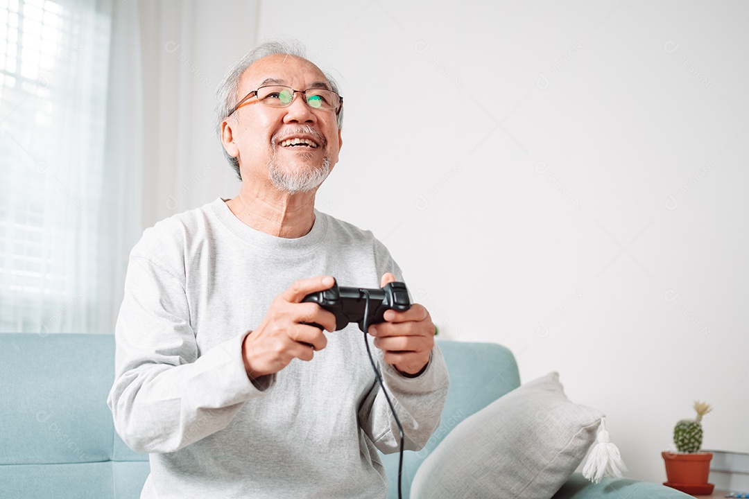 Homem sênior asiático se divertindo jogando vídeo em casa
