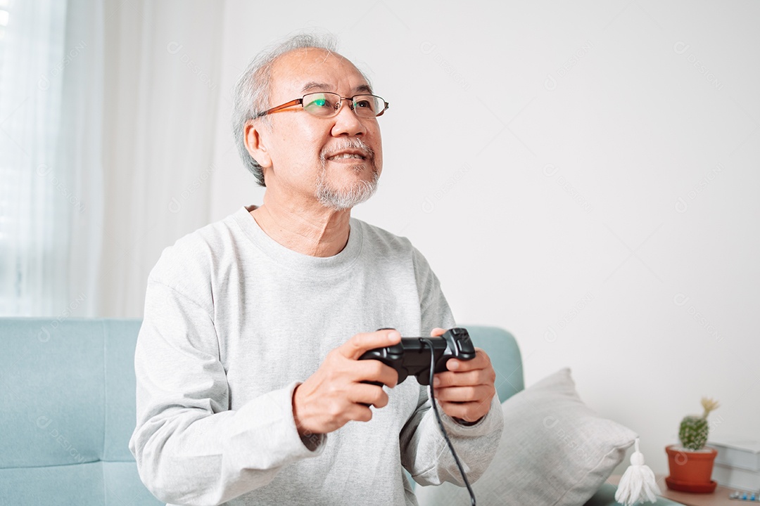 Homem sênior asiático se divertindo jogando vídeo em casa
