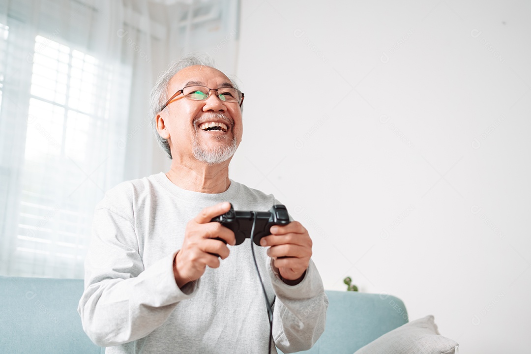 Homem sênior asiático se divertindo jogando vídeo em casa