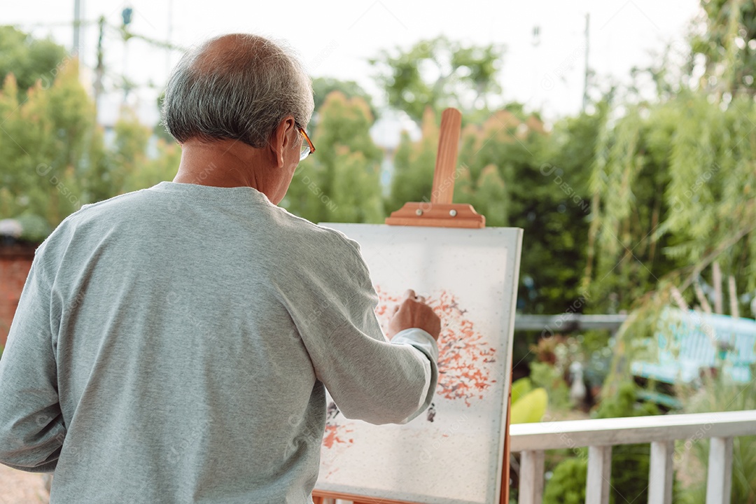 Homem idoso feliz pintando tela