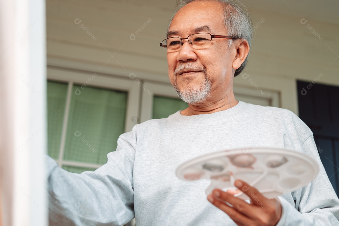 Homem idoso alegre pintando tela