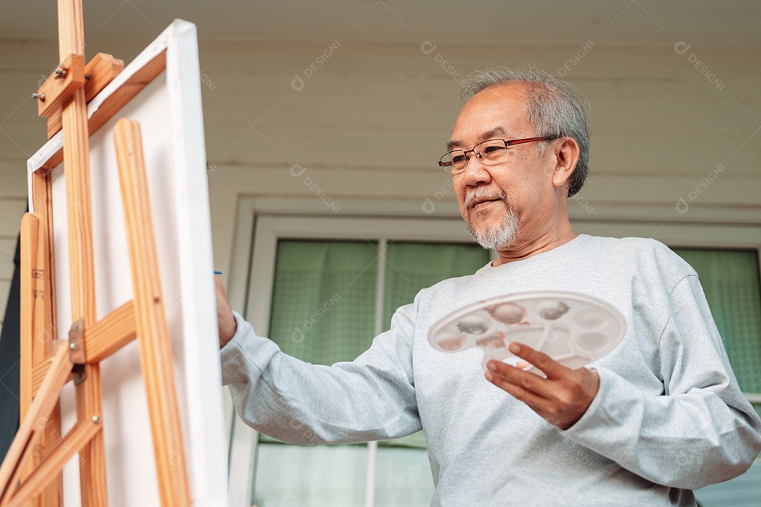 Homem idoso alegre pintando tela