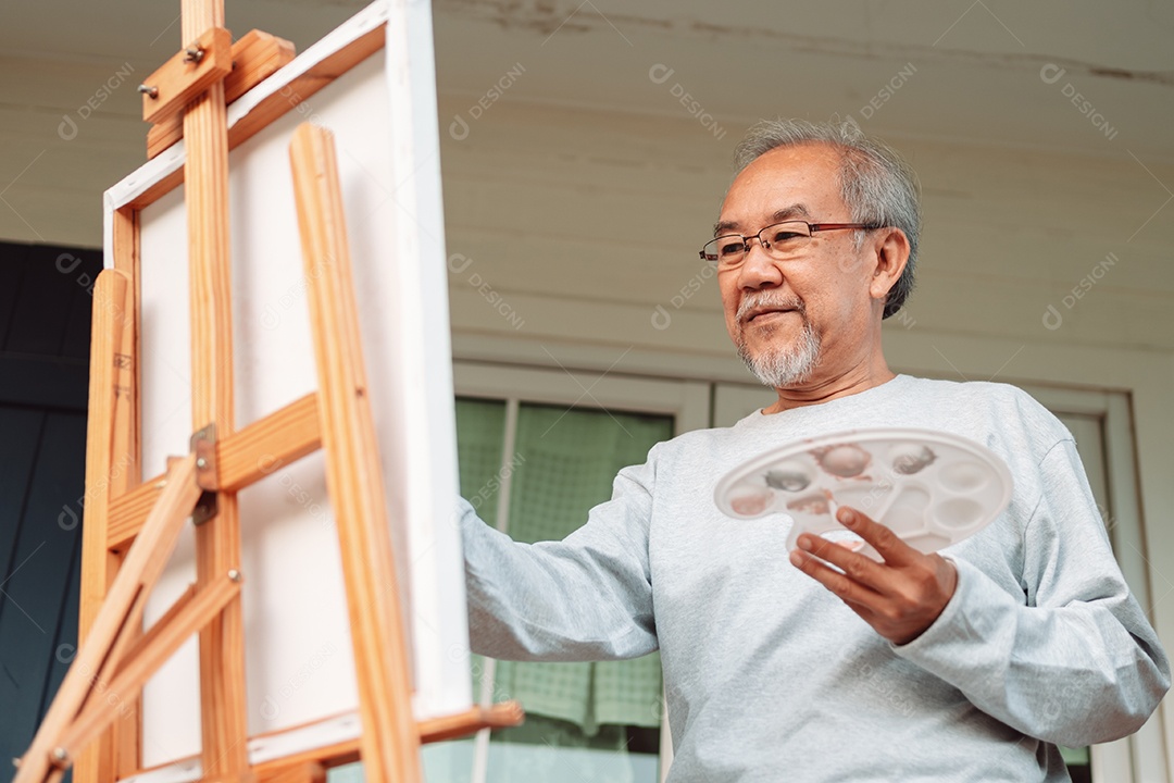 Homem idoso alegre pintando tela