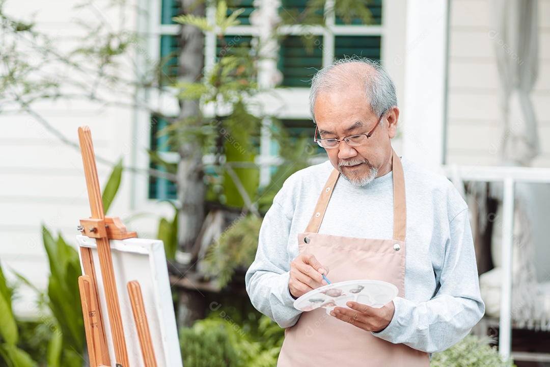 Homem idoso alegre pintando tela