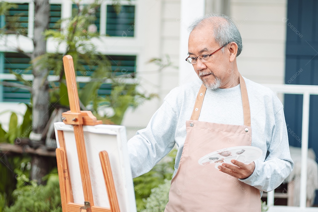 Homem idoso alegre pintando tela