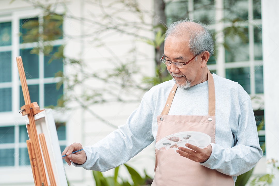 Homem idoso alegre pintando tela