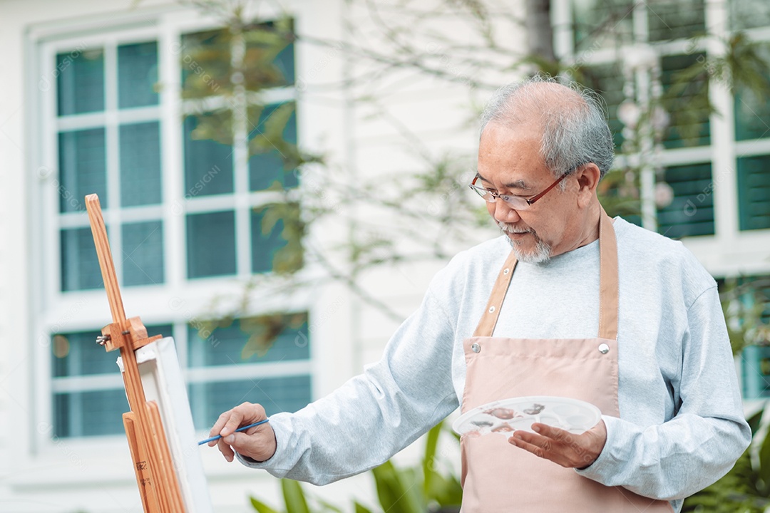 Homem idoso alegre pintando tela