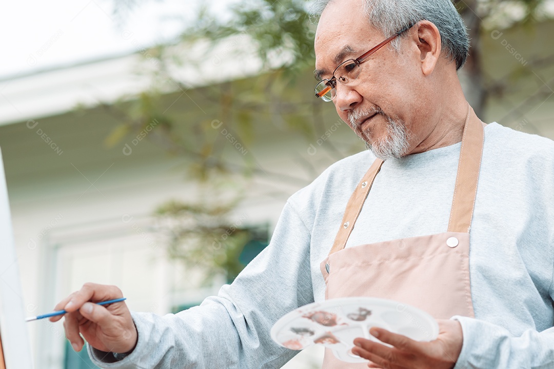 Homem idoso alegre pintando tela