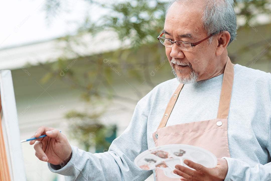 Homem idoso alegre pintando tela