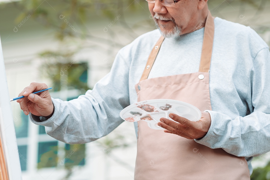 Homem idoso alegre pintando tela