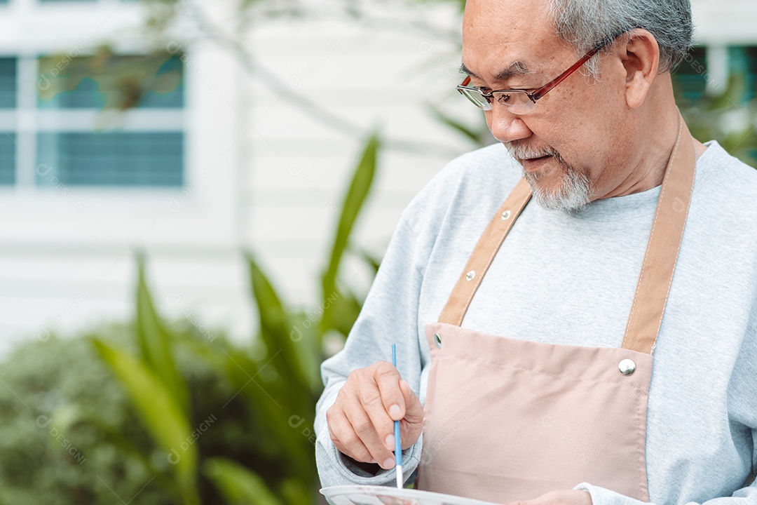 Homem idoso alegre pintando tela