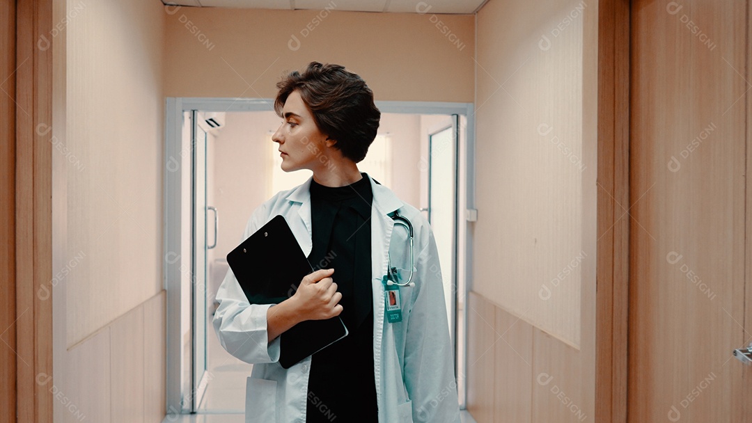 Médica de jaleco branco andando pelo corredor do hospital