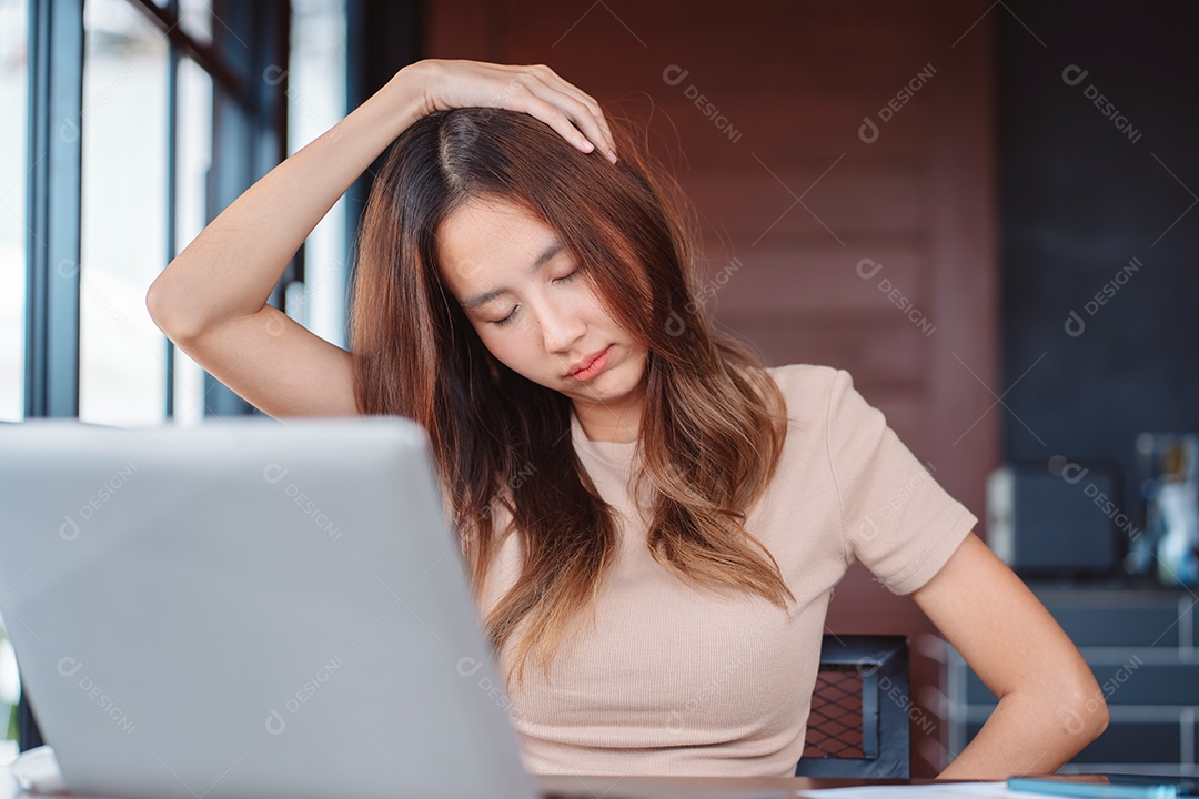 Mulher asiática com dor no pescoço durante o trabalho com laptop no escritório