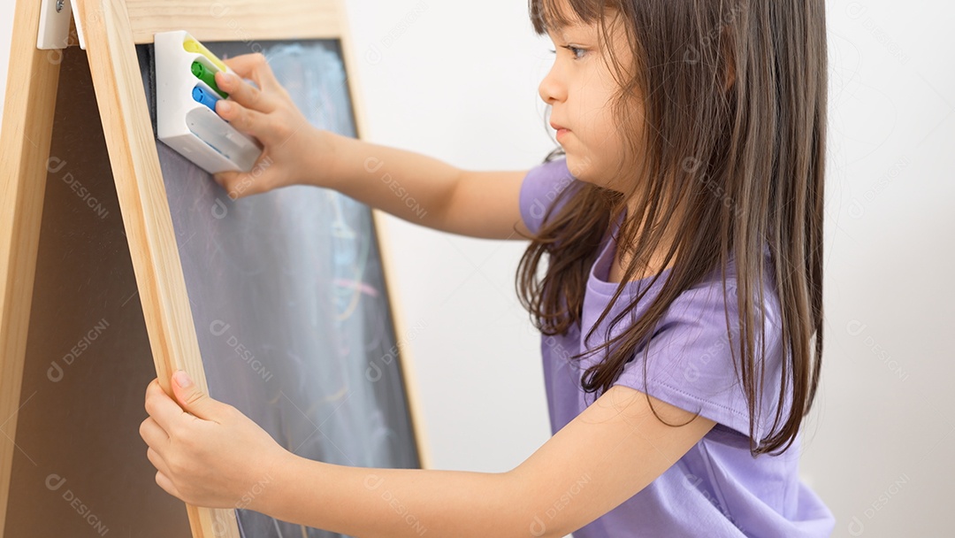Menina apagando o quadro-negro na aula com a esponja.