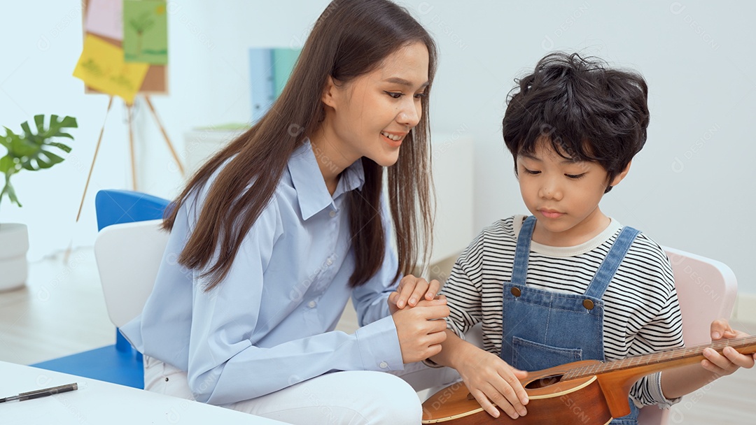 Jovem professor asiático ensinando violão e ukulele para seu garotinho.