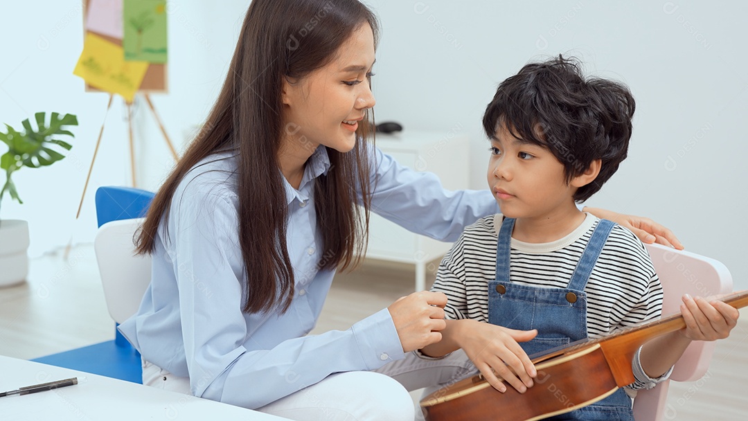Jovem professor asiático ensinando violão e ukulele para seu garotinho.