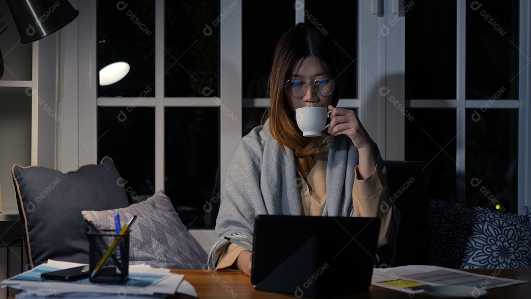 Empresária asiática ou freelancer trabalhando duro à noite olhando o tablet digital