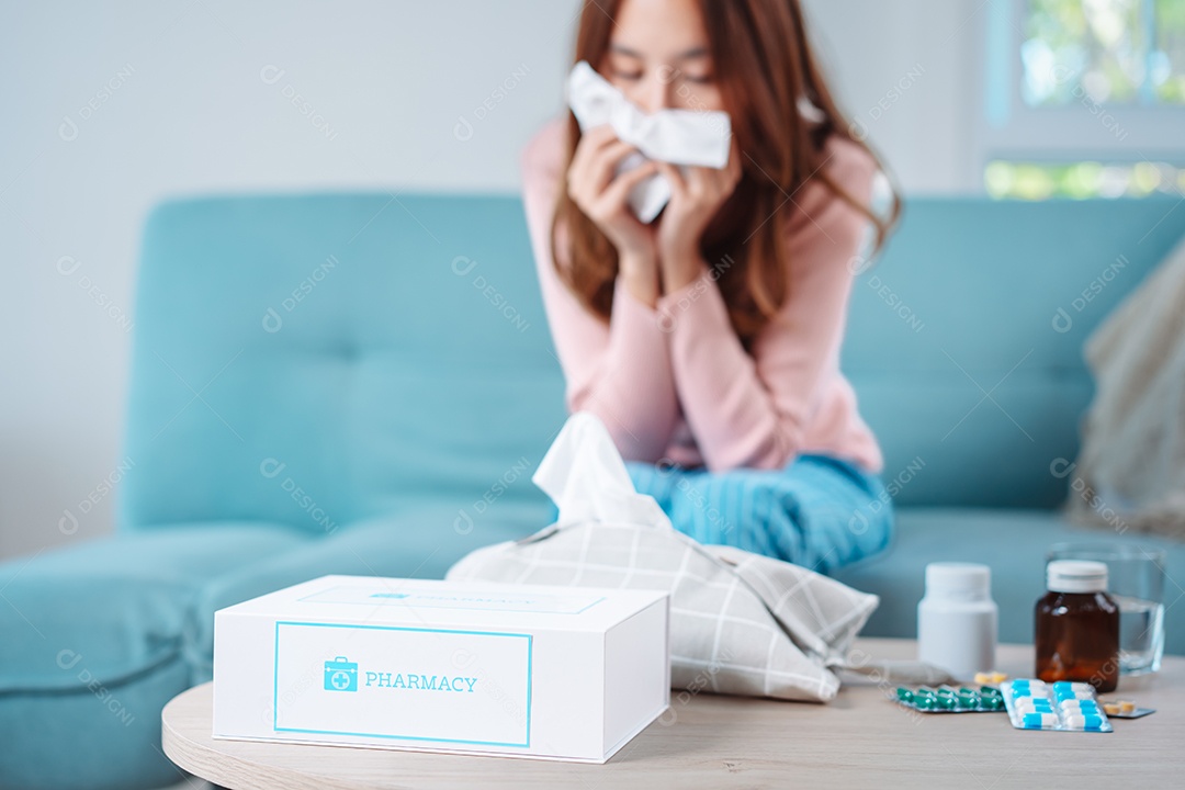 Paciente jovem asiática doente com frio ela espirra com lenço de papel no sofá